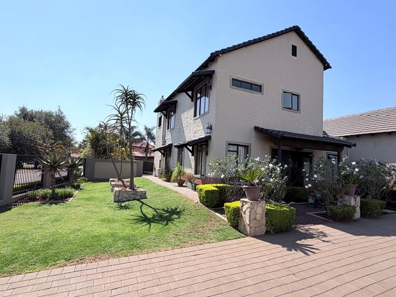 A well-maintained double-story residential property featuring a paved driveway, landscaped garden, and attached garage with a tiled roof.