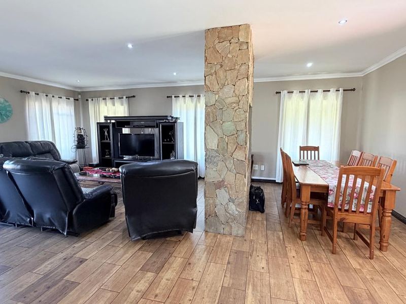 Spacious open-plan living and dining area featuring wood-look tile flooring, recessed lighting, and a prominent stone-clad central pillar.
