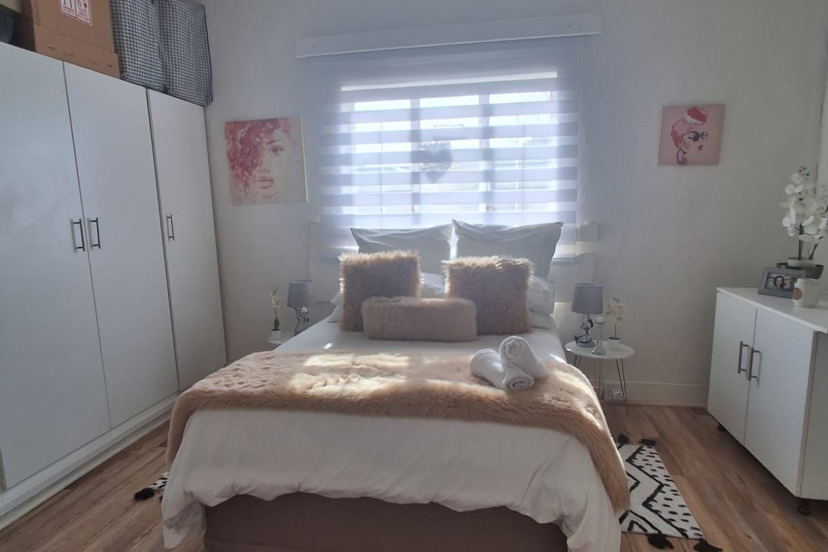 A well-lit bedroom featuring laminate flooring, built-in cupboards, and a neutral color palette, offering a comfortable and functional living space.