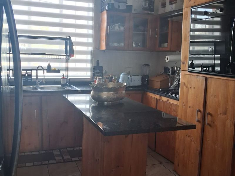 A functional kitchen featuring wooden cabinetry, granite countertops, a built-in oven, and tiled flooring, offering a classic layout with ample storage space.