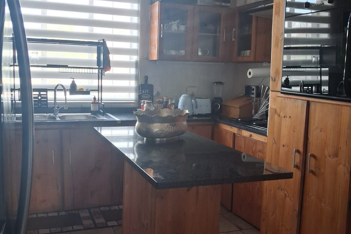 A functional kitchen featuring wooden cabinetry, granite countertops, a built-in oven, and tiled flooring, offering a classic layout with ample storage space.