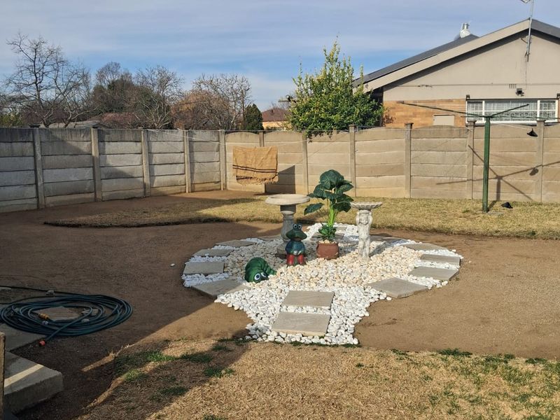 A rear garden area featuring a precast concrete boundary wall, a central decorative stone feature, and a rotary clothesline.
