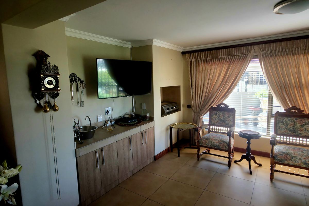 A living area featuring built-in cabinetry with an integrated sink, tiled flooring, and a built-in wall niche, offering a functional and versatile space.