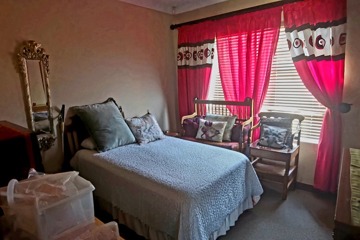 A cozy bedroom featuring a window with fitted curtain rods and neutral wall finishes.