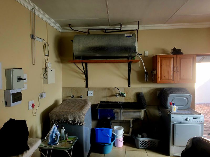 Functional laundry area featuring a stainless steel double sink, wall-mounted geyser, and direct access to the exterior.