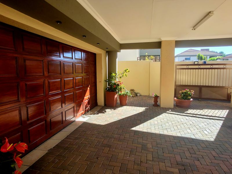 A well-maintained covered carport area featuring a polished wooden sectional garage door and durable paved flooring.