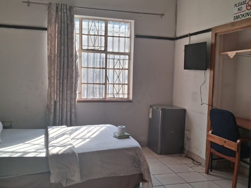 A bedroom featuring tiled flooring, a decorative pressed metal ceiling, and a built-in alcove, currently showing signs of wear and ceiling water damage.