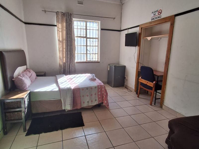 A bedroom featuring tiled flooring, a built-in closet, and an ornate pressed metal ceiling, currently showing signs of wear and ceiling water damage.