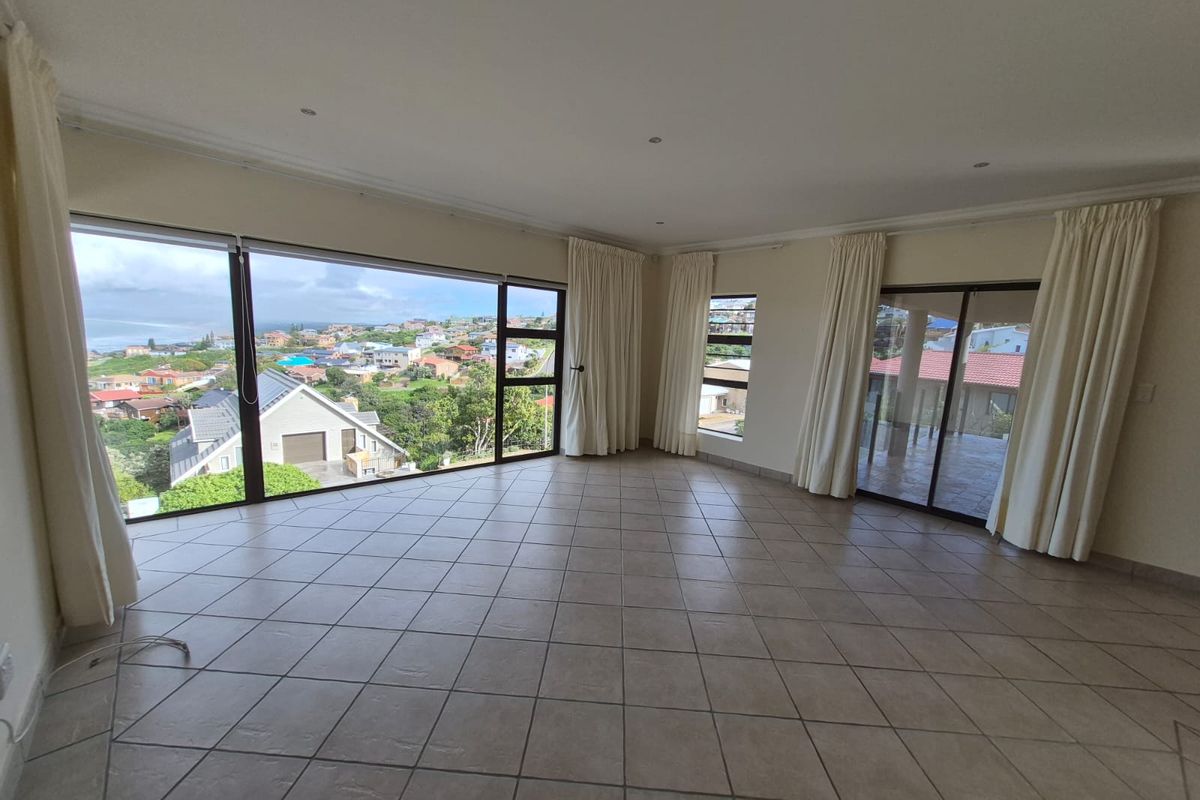Spacious, light-filled living area featuring large windows with expansive neighbourhood views, tiled flooring, and direct access to an outdoor patio.