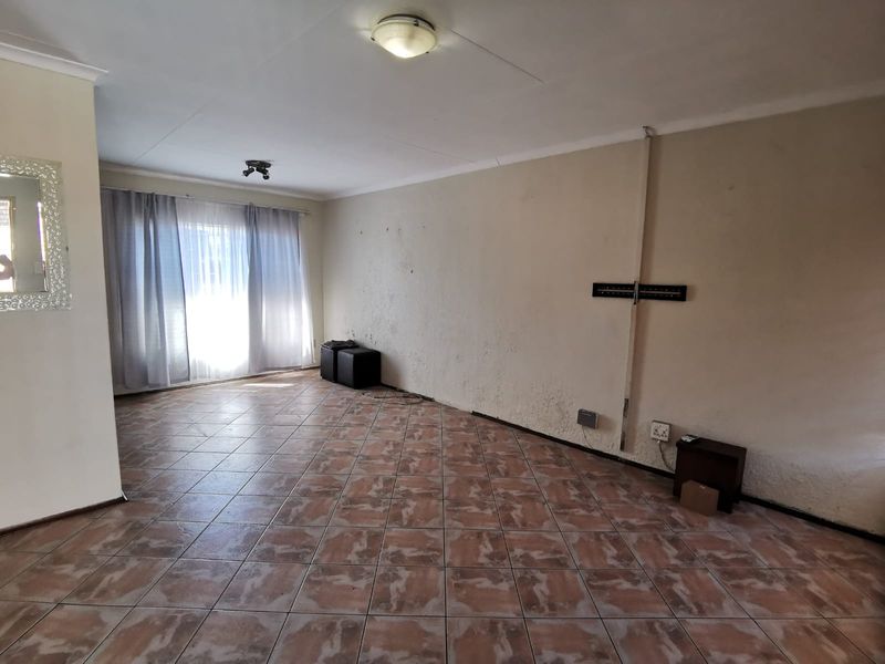 Spacious living area featuring tiled flooring and neutral walls, offering a blank canvas for personalization. Requires minor cosmetic updates to wall finishes.