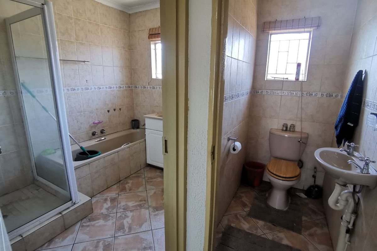 A dated bathroom featuring a separate shower and bathtub, alongside a separate toilet area with a pedestal basin and tiled finishes throughout.