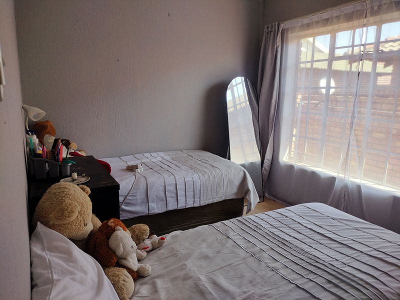 A functional bedroom featuring a window with security bars and neutral wall finishes, providing a comfortable space for rest.