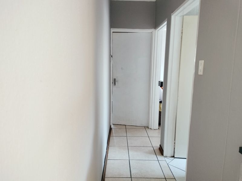 A functional hallway featuring neutral wall paint and tiled flooring, providing access to multiple rooms within the home.
