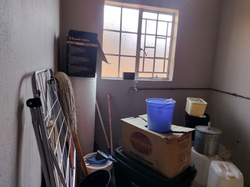 A utility or laundry space featuring a window and a wall-mounted water tap, currently used for storage.
