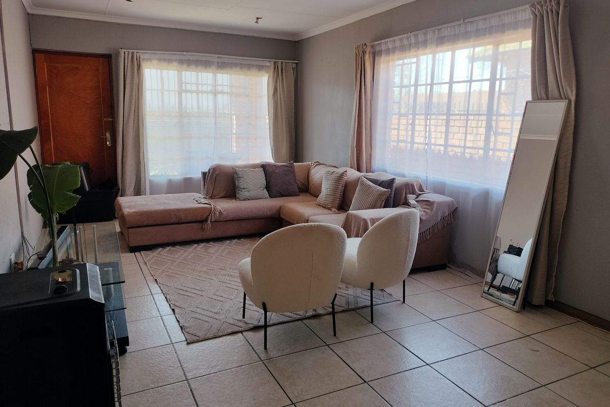 A spacious living room featuring neutral tiled flooring and large windows that provide ample natural light.