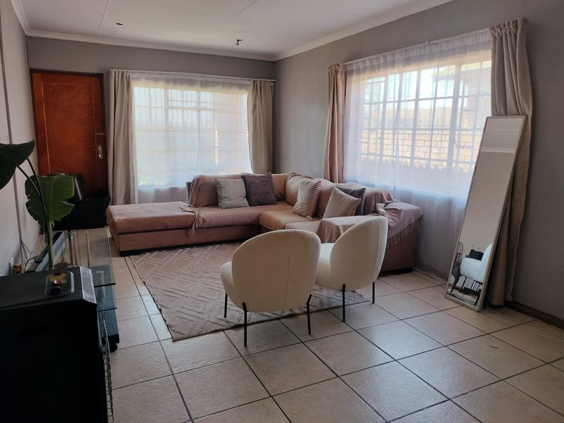 A spacious living room featuring neutral tiled flooring and large windows that provide ample natural light.