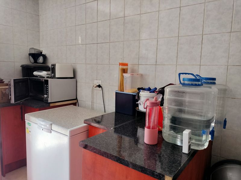A functional scullery area featuring built-in cabinetry, granite countertops, and full-height wall tiling, providing practical workspace and storage.