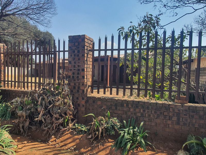 Front view of the property featuring a brick boundary wall with steel palisade fencing and brick pillars.