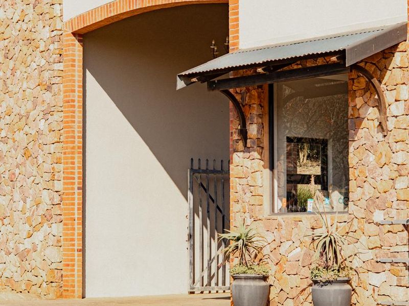 A well-maintained exterior facade featuring natural stone cladding, a brick archway, and a metal awning over a window.