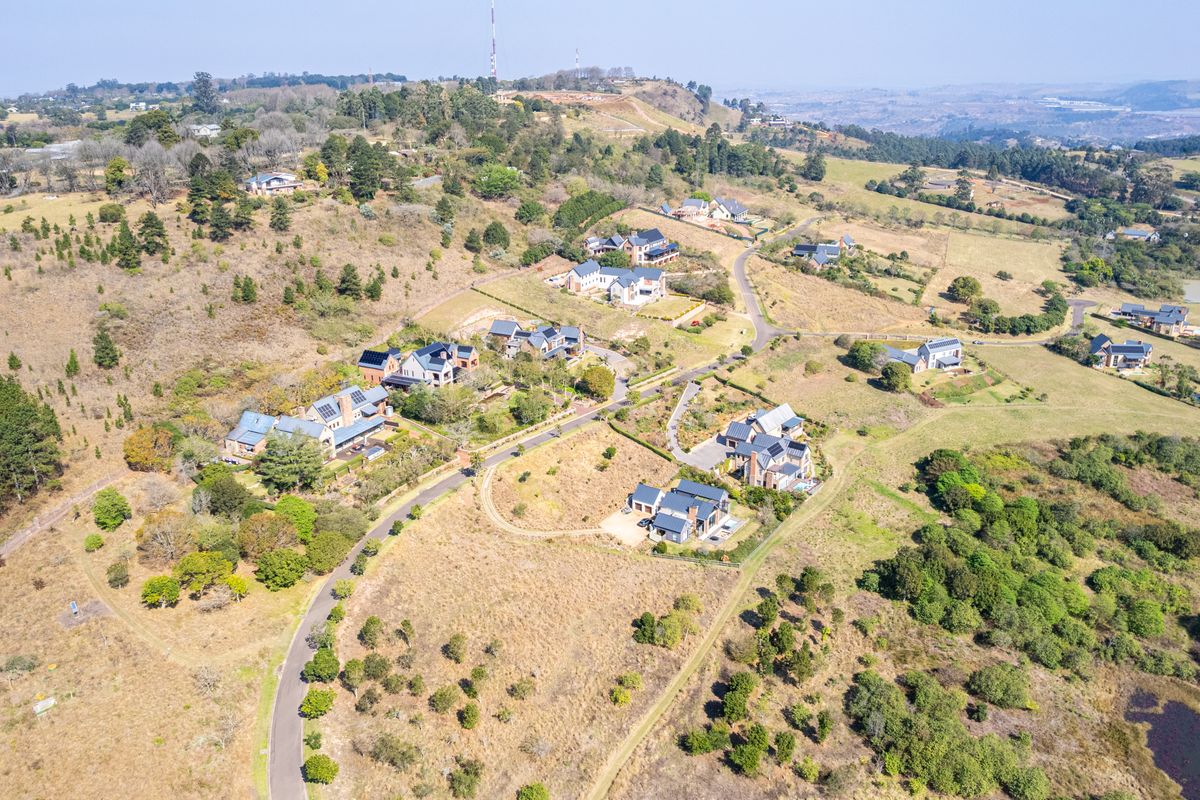 An aerial view of a residential estate featuring multiple homes, paved access roads, and surrounding natural landscape.