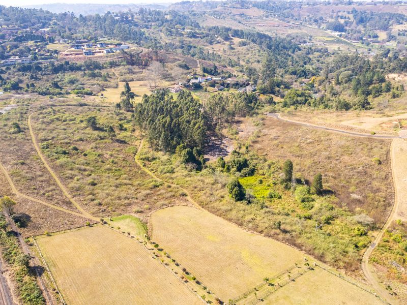 An aerial view of a large, undeveloped residential land parcel featuring natural vegetation, open fields, and surrounding rural landscape.