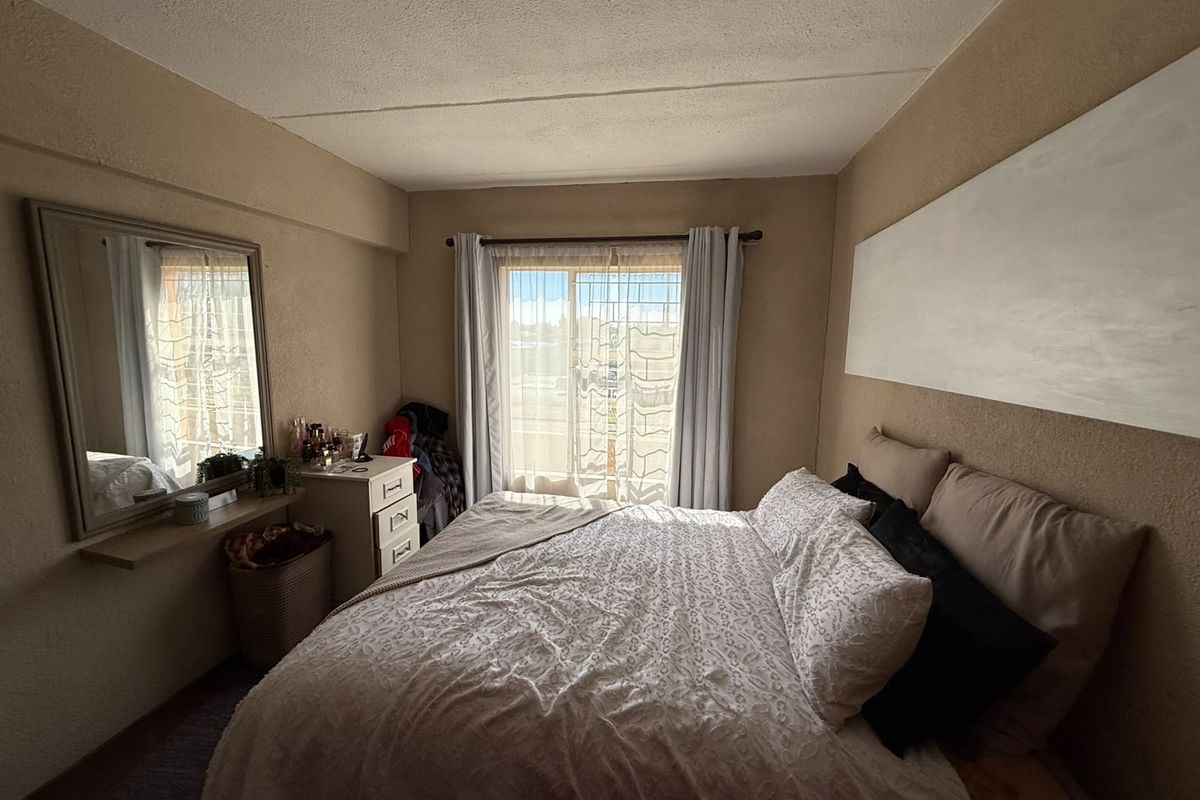A bedroom featuring a sliding glass door with natural light, neutral wall finishes, and a wall-mounted shelf.