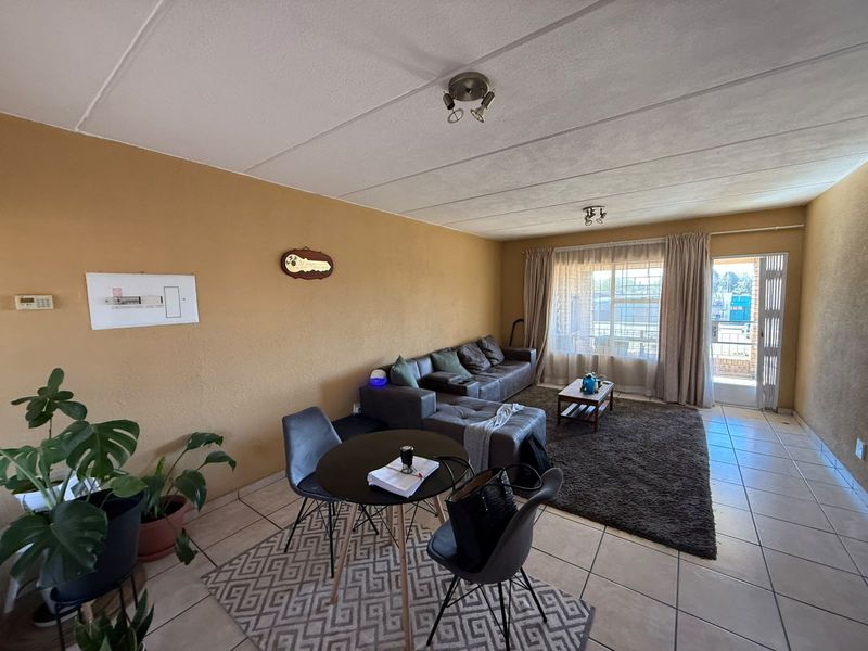 Open-plan living and dining area featuring tiled flooring, direct access to an outdoor space, and a visible electrical distribution board.