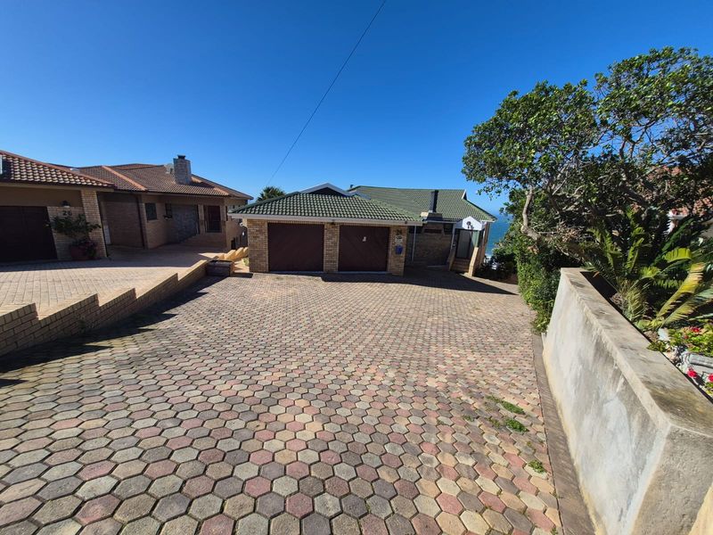 Front view of the property featuring a paved driveway leading to a double garage with a tiled roof.