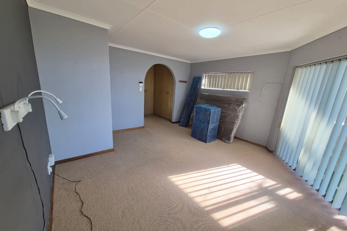 A spacious bedroom featuring built-in cupboards, an arched doorway, and neutral wall tones, offering a blank canvas for personalization.