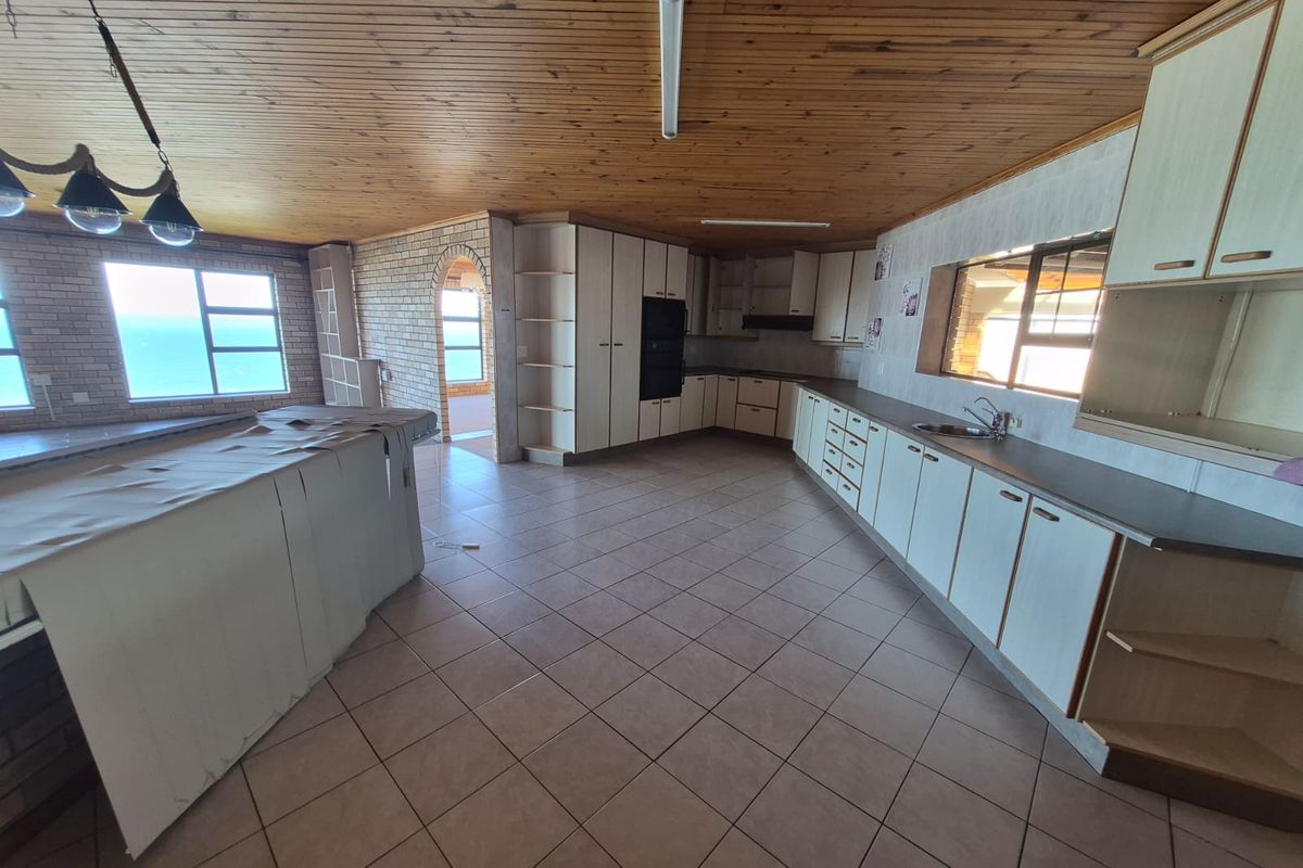 Spacious kitchen featuring extensive built-in cabinetry, timber ceilings, and tiled flooring, offering a functional layout with potential for modern updates.