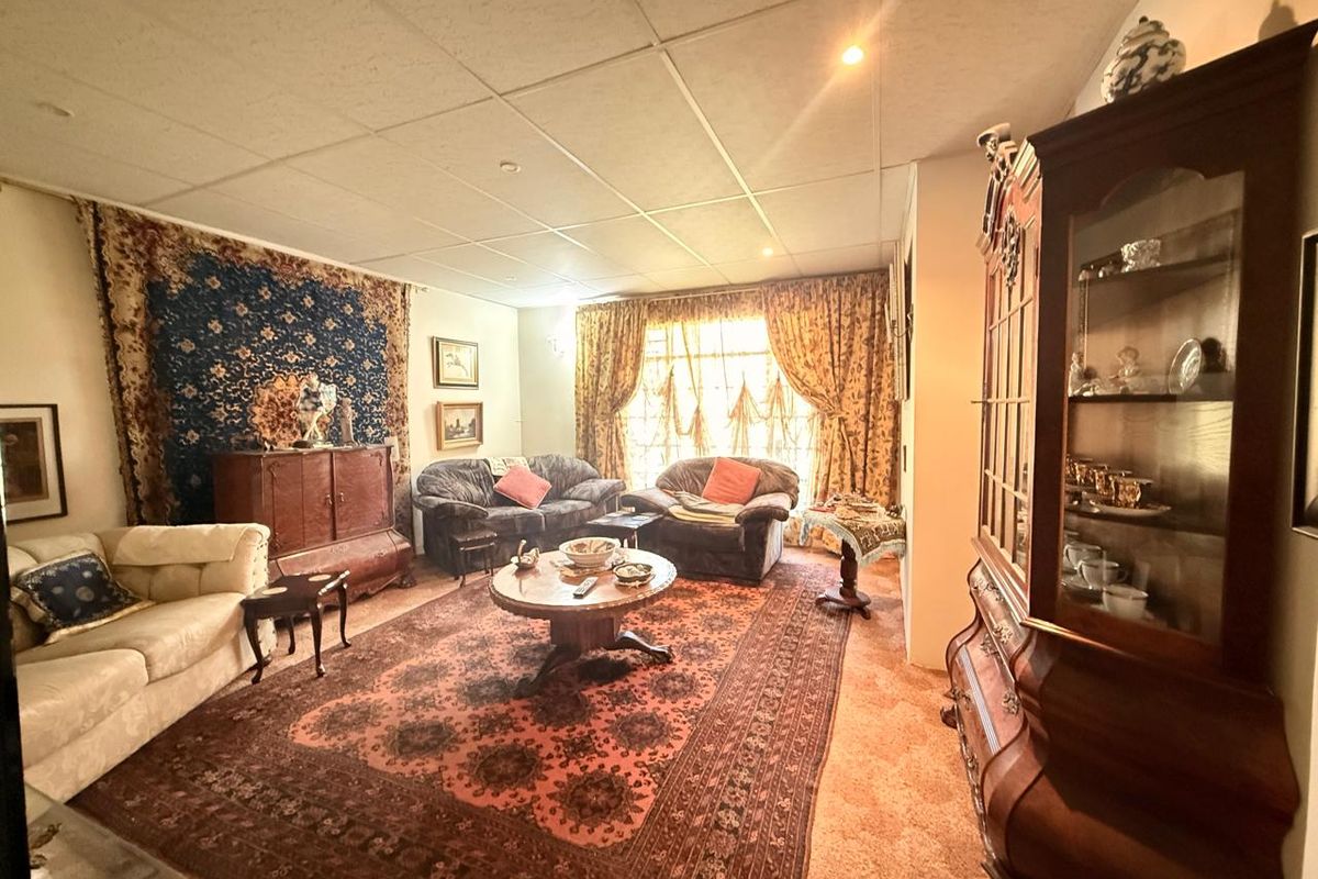 A traditional living room featuring a suspended ceiling with recessed lighting and large windows, offering a classic layout ready for modern updates.