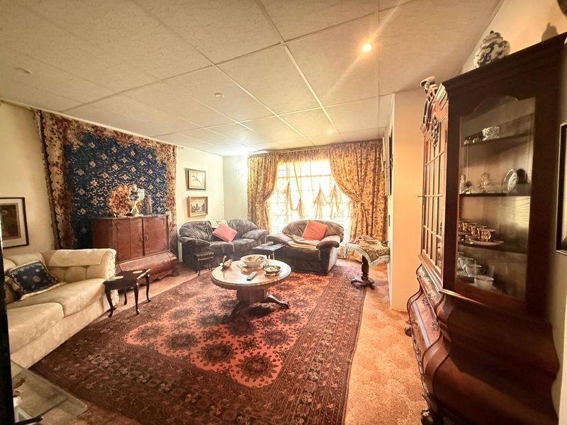 A traditional living room featuring a suspended ceiling with recessed lighting and large windows, offering a classic layout ready for modern updates.