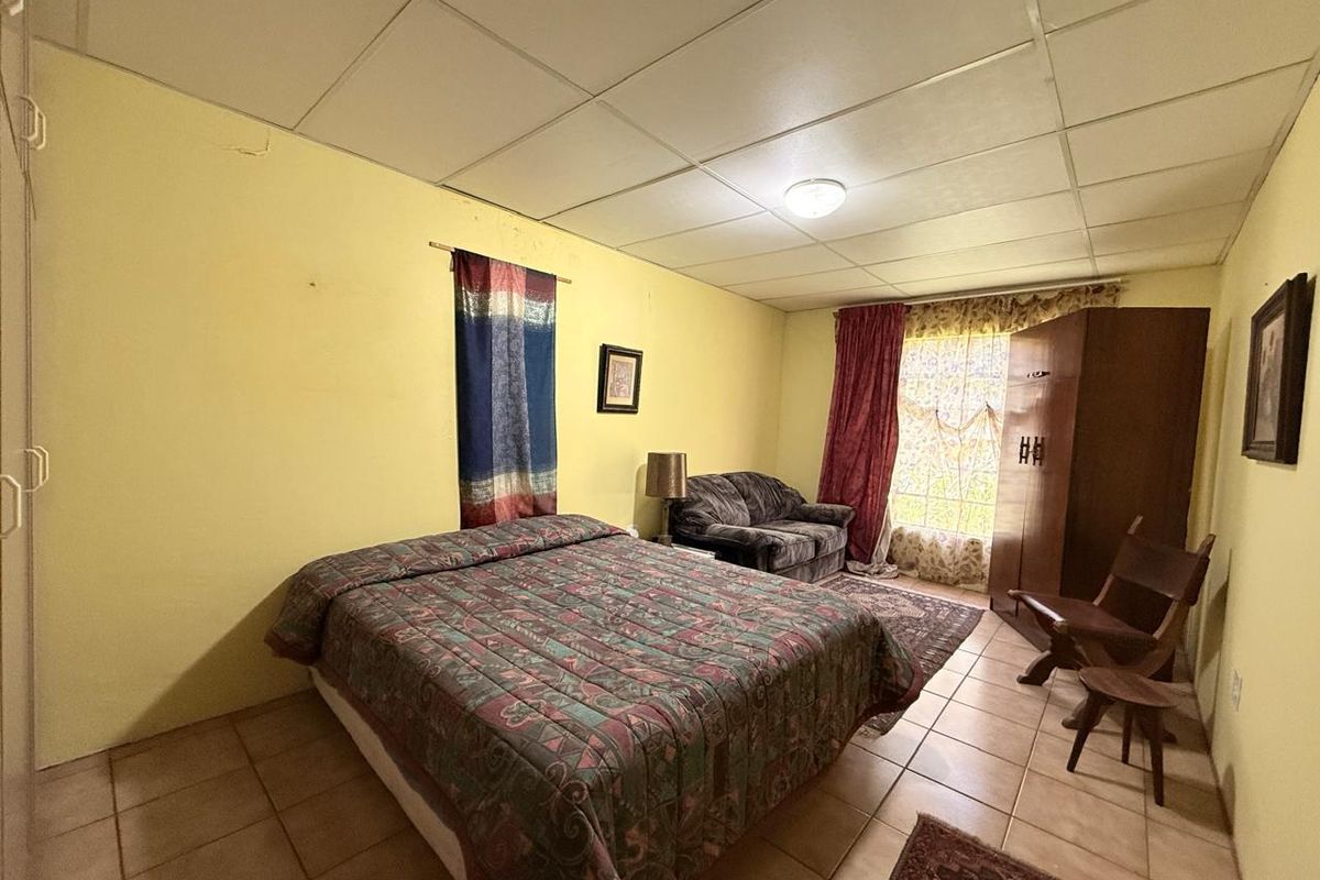 A bedroom featuring tiled flooring and a drop ceiling, requiring cosmetic updates to improve the overall aesthetic and finish.
