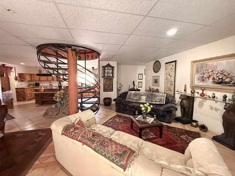 Open plan living area featuring a prominent spiral staircase, tiled flooring, and an adjoining kitchen with traditional cabinetry.