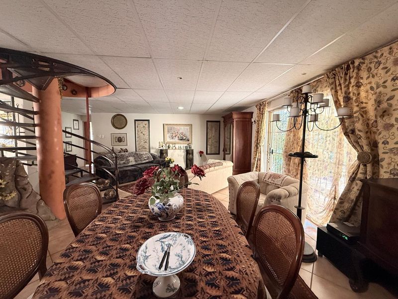 Open plan living and dining area featuring a distinctive spiral staircase, tiled flooring, and sliding glass doors leading to the exterior.