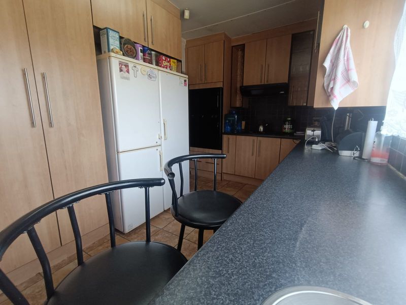 A functional kitchen featuring laminate cabinetry, dark countertops, built-in oven, extractor fan, and tiled flooring with a tiled backsplash.