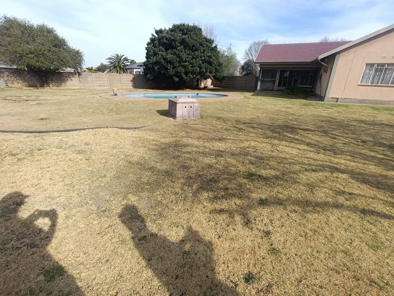 Spacious rear garden featuring a swimming pool, perimeter walling, and a covered patio area attached to the main house.
