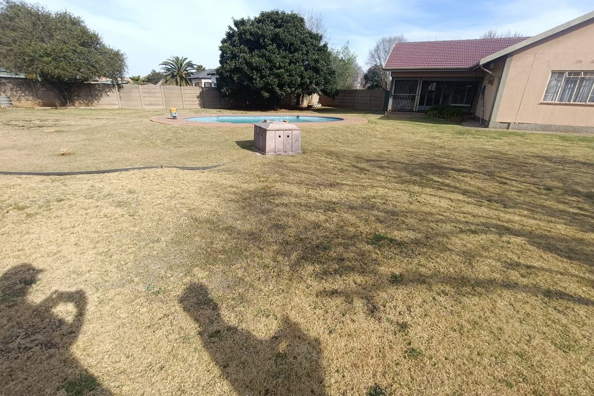 Spacious rear garden featuring a swimming pool, perimeter walling, and a covered patio area attached to the main house.
