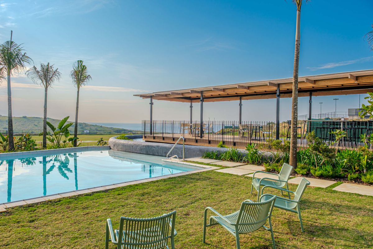 A well-maintained outdoor pool area featuring a swimming pool, a covered patio structure, and landscaped garden space with scenic views.