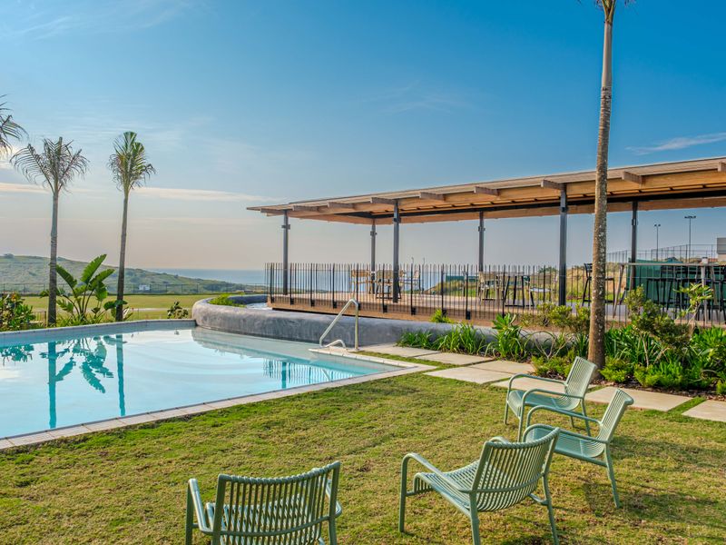 A well-maintained outdoor pool area featuring a swimming pool, a covered patio structure, and landscaped garden space with scenic views.