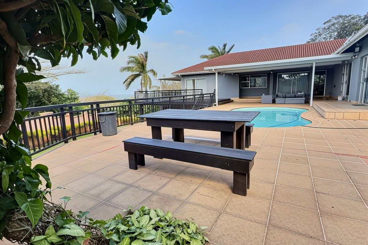 Spacious outdoor patio area featuring a swimming pool, tiled flooring, and metal balustrades, offering a functional space for relaxation and outdoor entertainment.