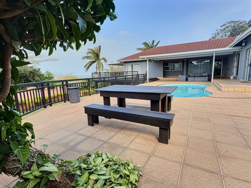 Spacious outdoor patio area featuring a swimming pool, tiled flooring, and metal balustrades, offering a functional space for relaxation and outdoor entertainment.