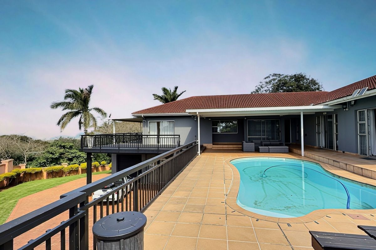Spacious outdoor entertainment area featuring a swimming pool, tiled pool deck, and a covered patio with elevated balcony views.