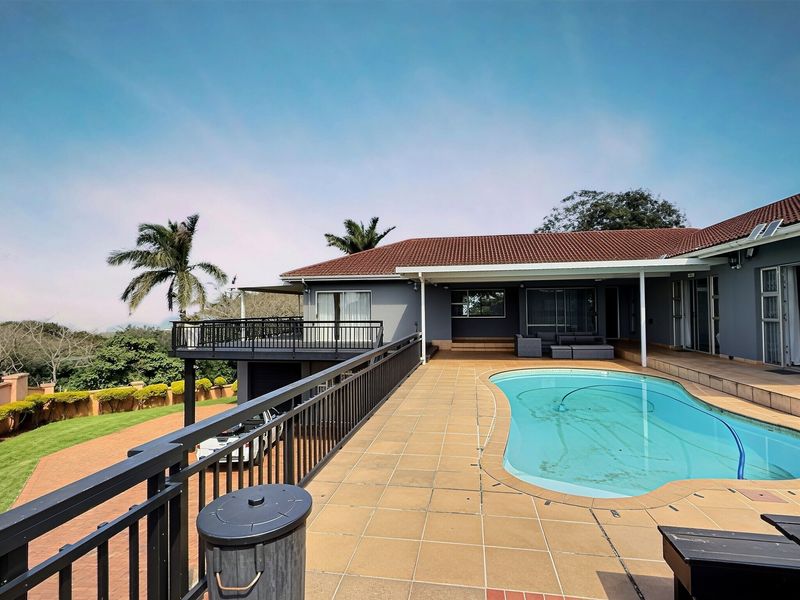 Spacious outdoor entertainment area featuring a swimming pool, tiled pool deck, and a covered patio with elevated balcony views.