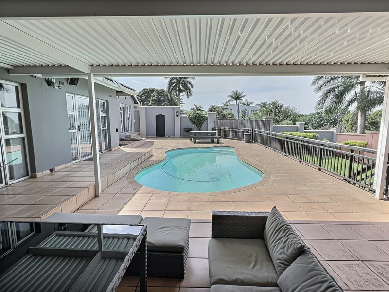 Spacious covered patio overlooking a private swimming pool with tiled decking, secure metal railings, and direct access to the main building via sliding doors.