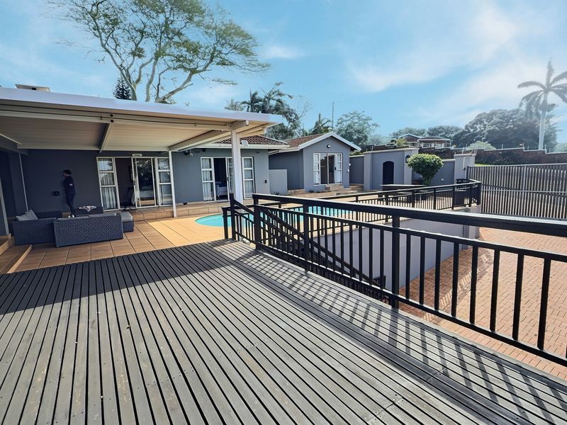 Spacious outdoor entertainment area featuring a swimming pool, extensive timber decking, and a covered patio overlooking the guest house grounds.