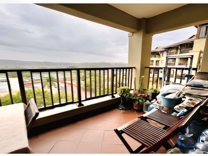 A covered balcony featuring tiled flooring and a metal balustrade, offering elevated views of the surrounding estate.