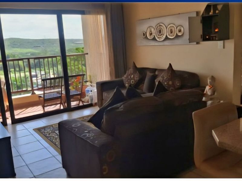 Open plan living area featuring tiled floors and large sliding glass doors leading to a balcony with scenic views.