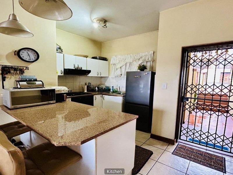 Functional kitchen featuring granite countertops, built-in cabinetry, and direct access to an outdoor area through a secure metal gate.