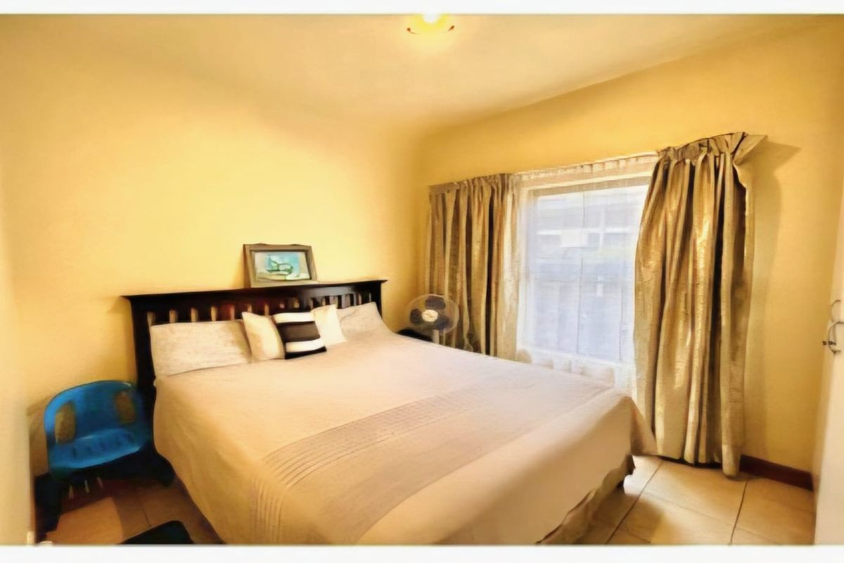 A standard bedroom featuring tiled flooring and a built-in wardrobe, offering a functional space with natural light.